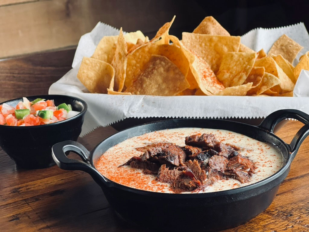 chips, salsa and brisket queso on the table
